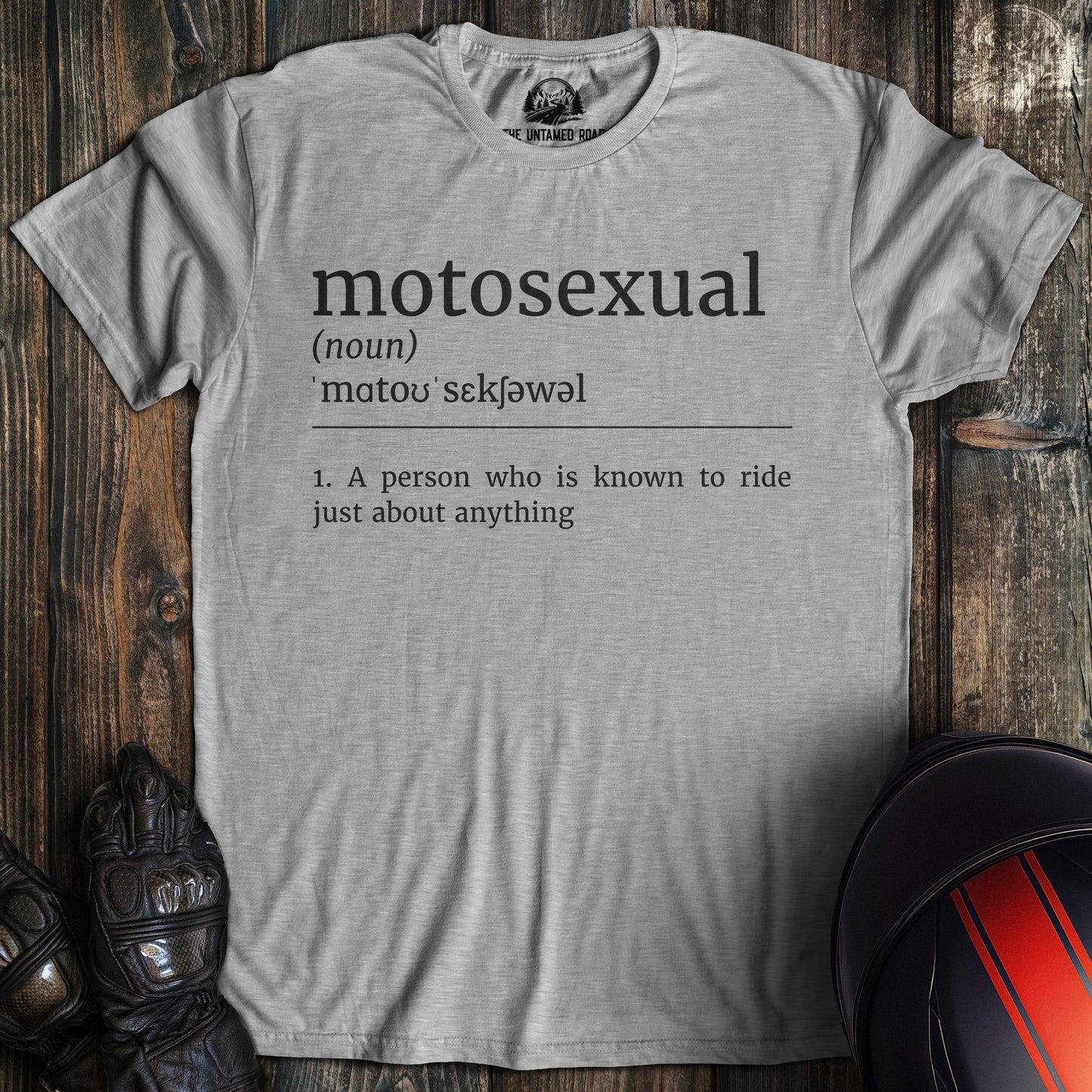 Gray t-shirt with 'motosexual' definition print on a wooden surface with motorcycle gear.