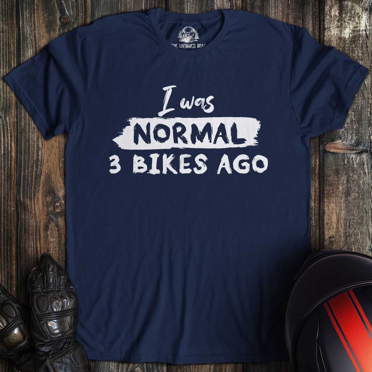 A navy colored t-shirt with the words "normal three bikes ago" printed on the front.