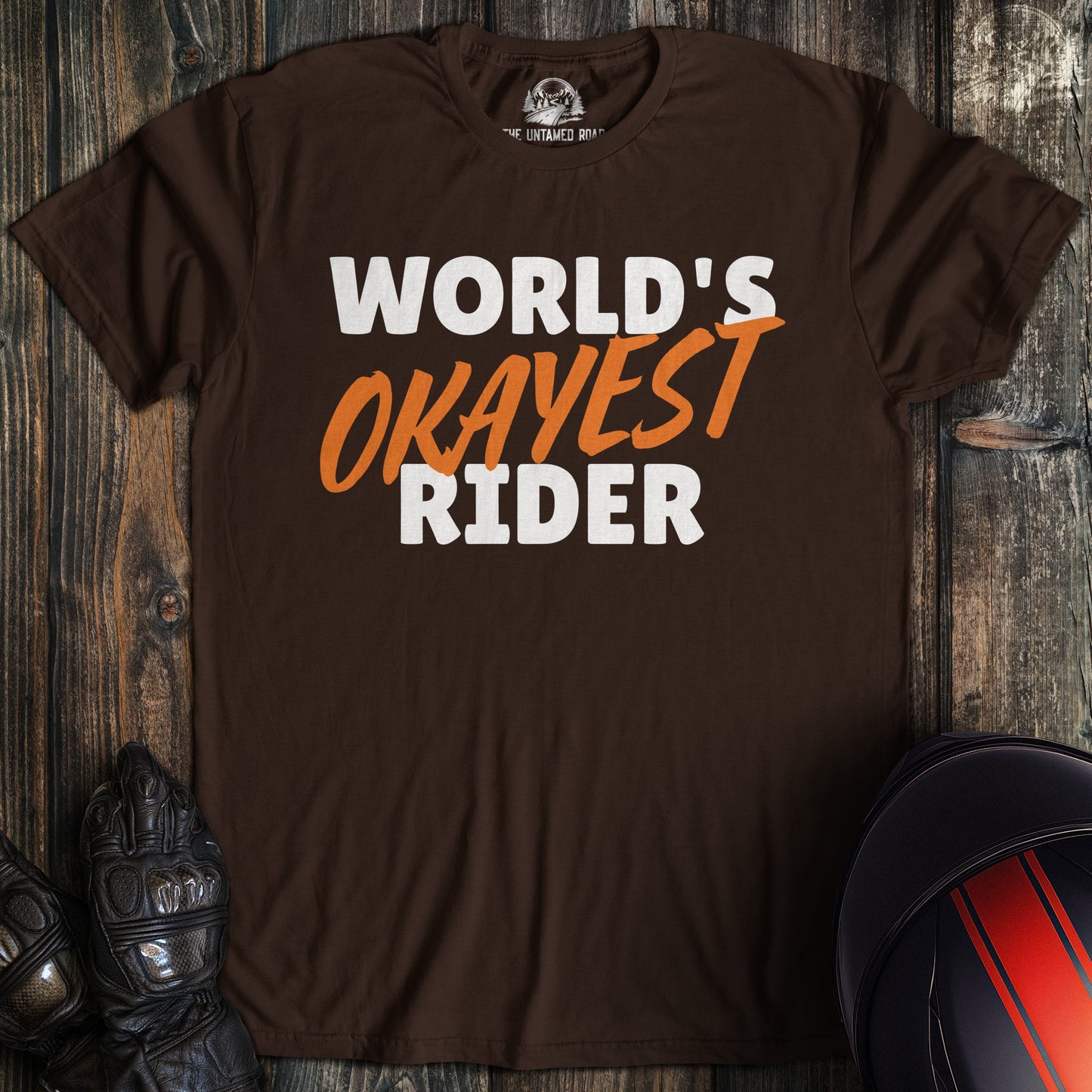 A dark chocolate colored t-shirt with the words "worlds okayest rider" printed on the front.