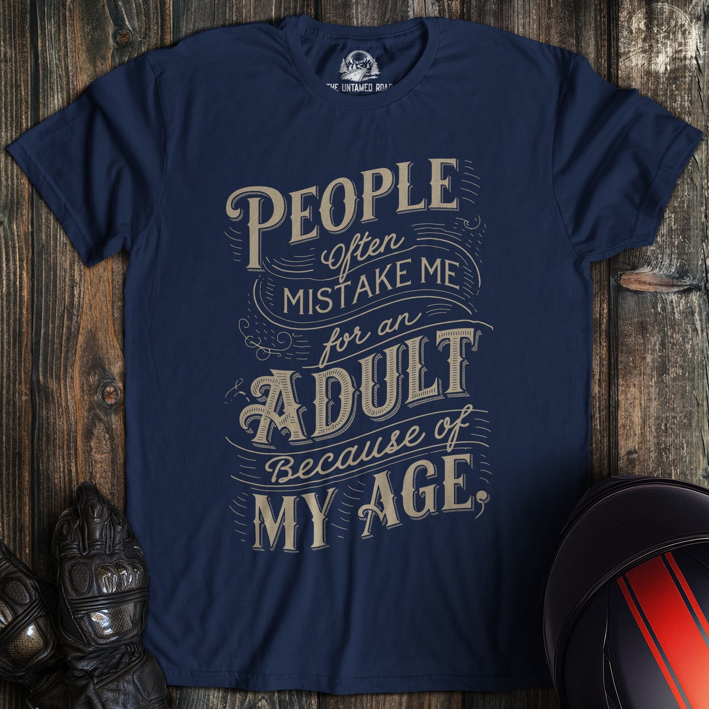 A navy colored t-shirt with the words "mistake me for adult" printed on the front.