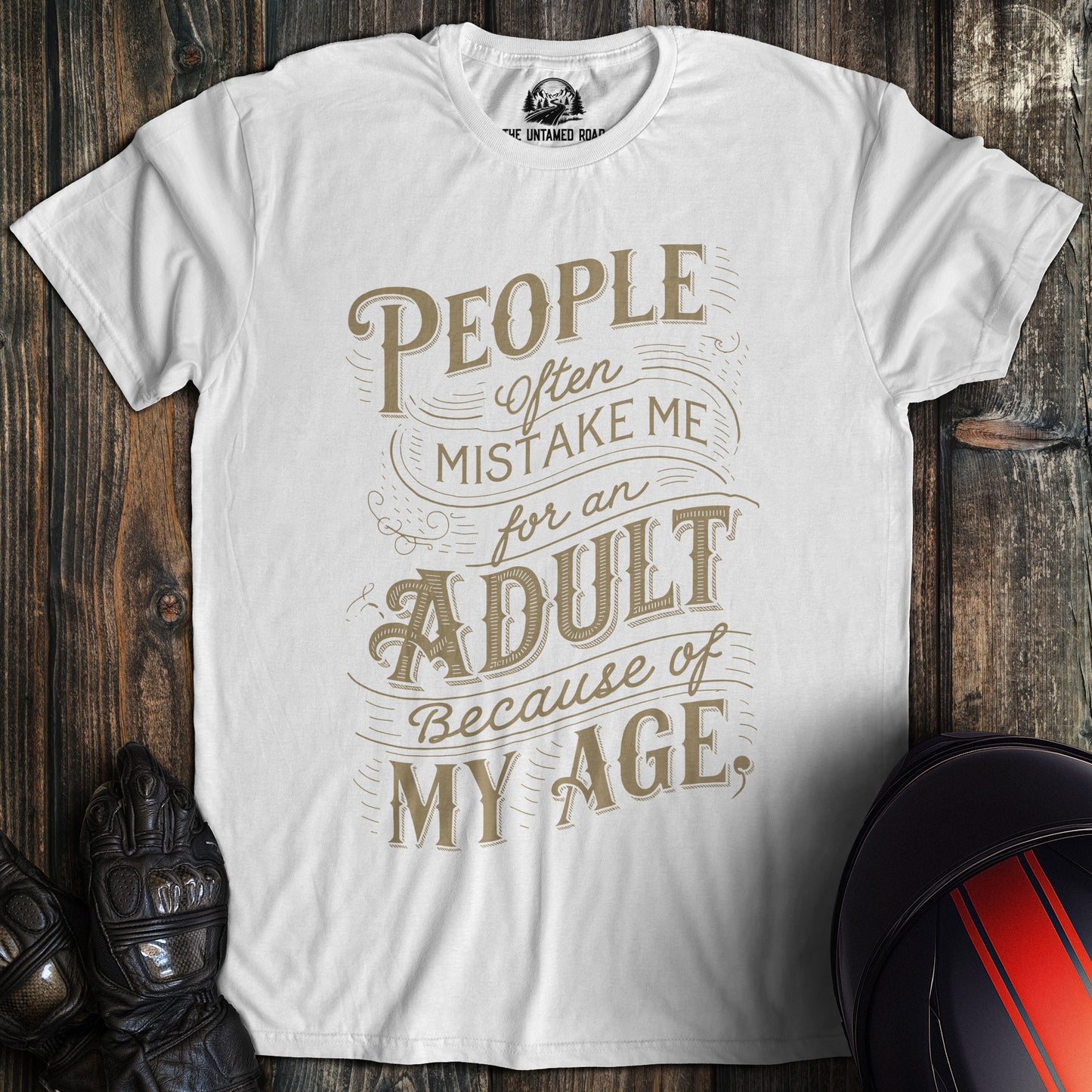 A white colored t-shirt with the words "mistake me for adult" printed on the front.