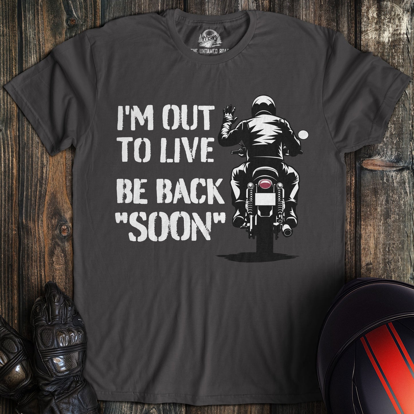 A charcoal colored t-shirt with the words "out to live be back soon" printed on the front.