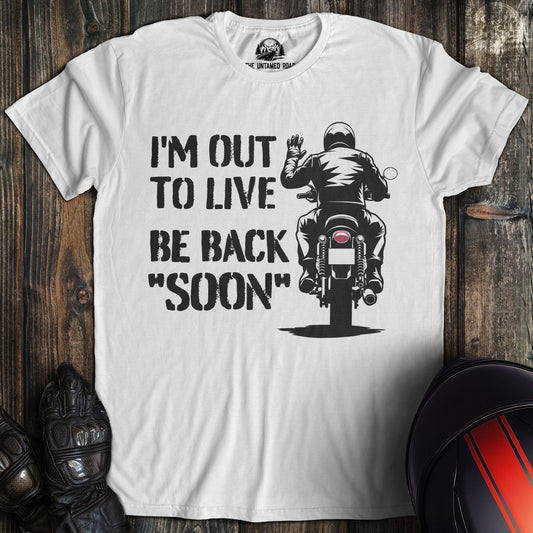 A white colored t-shirt with the words "out to live be back soon" printed on the front.