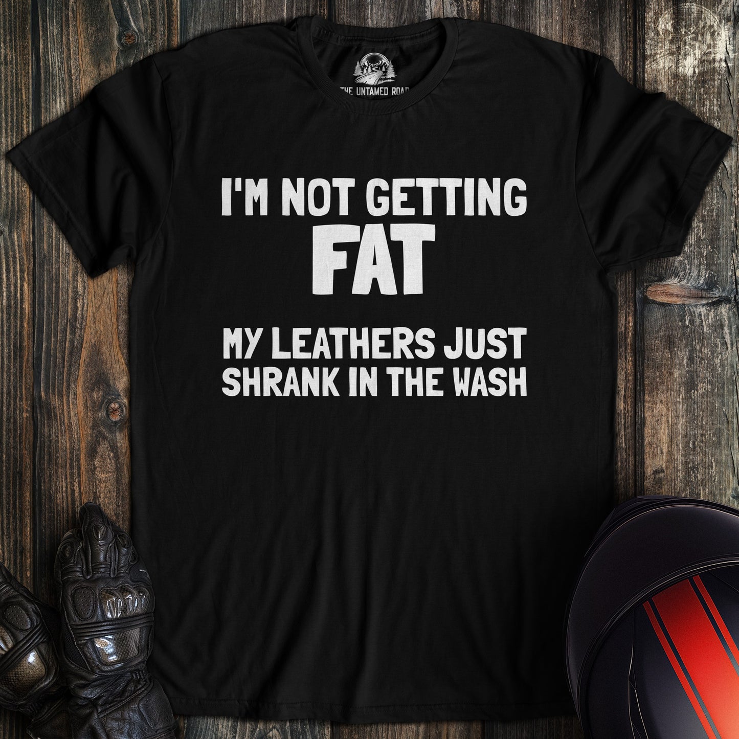 A black colored t-shirt with the words "not fat leathers shrank" printed on the front.