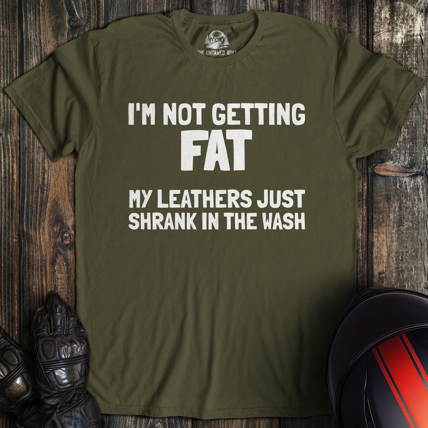 A military green colored t-shirt with the words "not fat leathers shrank" printed on the front.