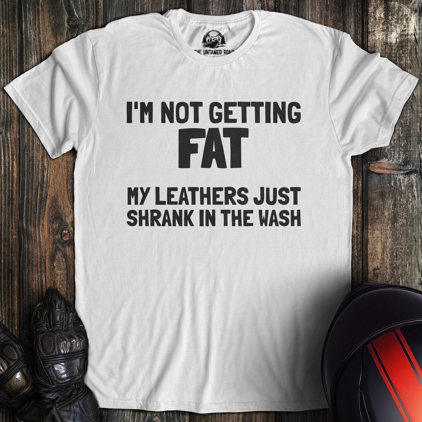 A white colored t-shirt with the words "not fat leathers shrank" printed on the front.