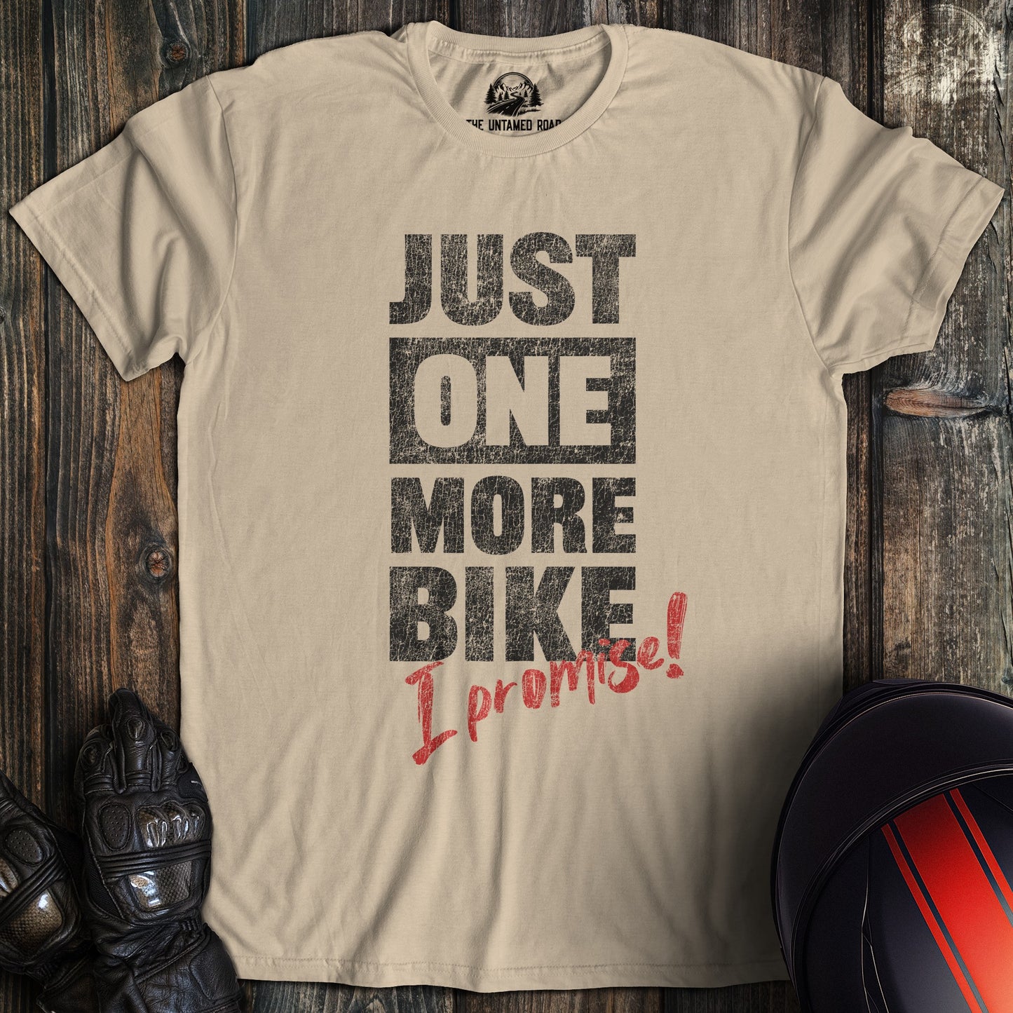 A sand colored t-shirt with the words "just one more bike" printed on the front.
