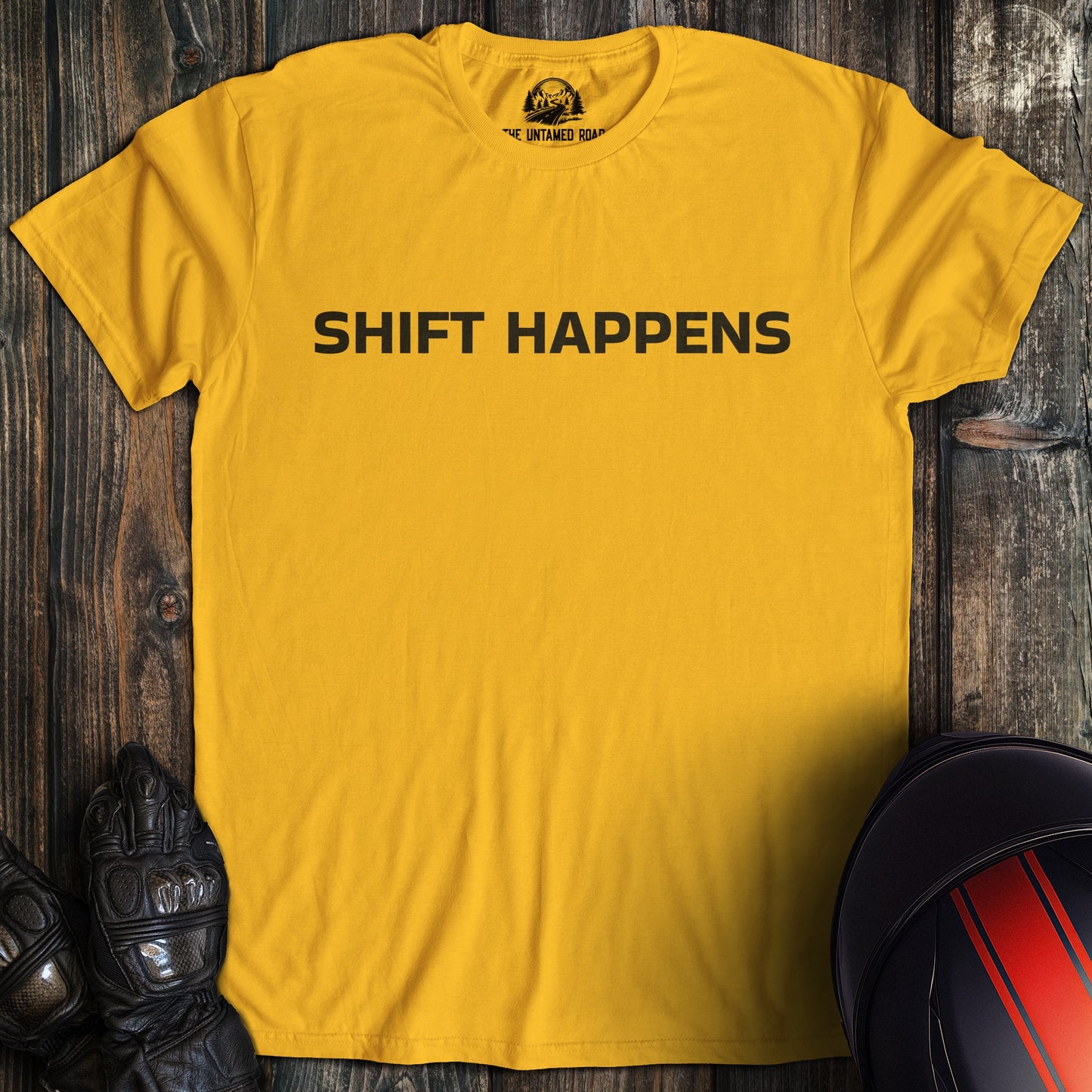 A gold colored t-shirt with the words "shift happens" printed on the front.