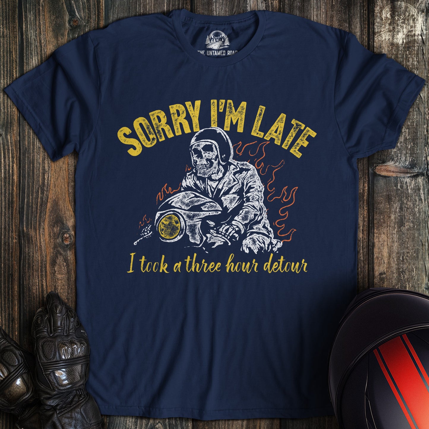 A navy blue t-shirt featuring a skeleton biker on a motorcycle with the text, Sorry I'm Late I took a three hour detour.
