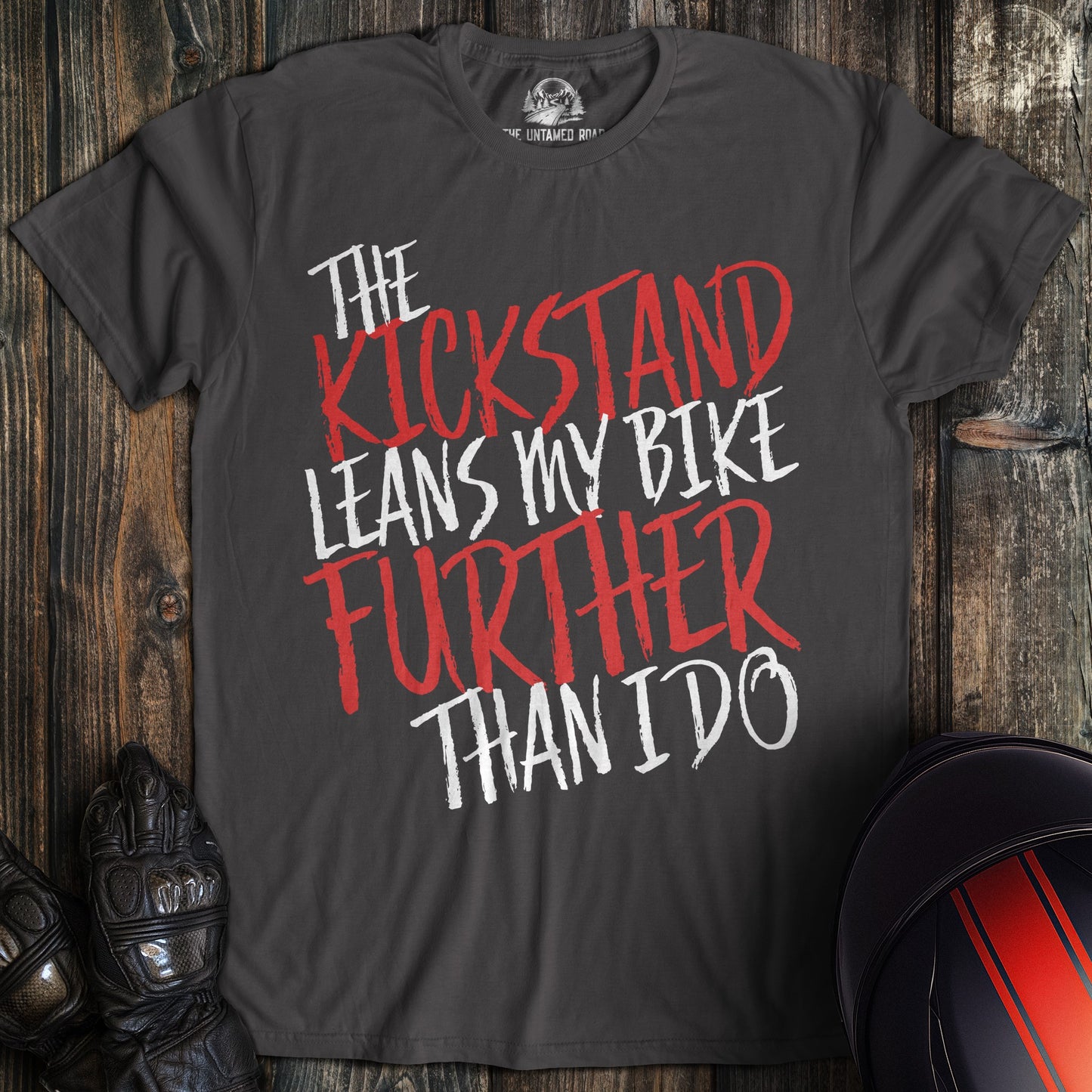 A charcoal colored t-shirt with the words "kickstand leans further" printed on the front.