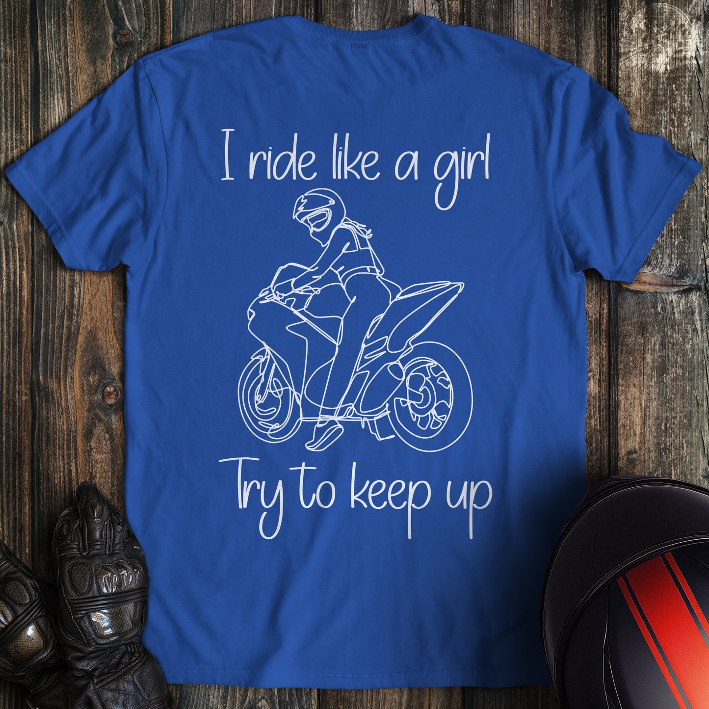 Royal blue t-shirt with a white line drawing of a biker on a motorcycle and the text, I ride like a girl Try to keep up.