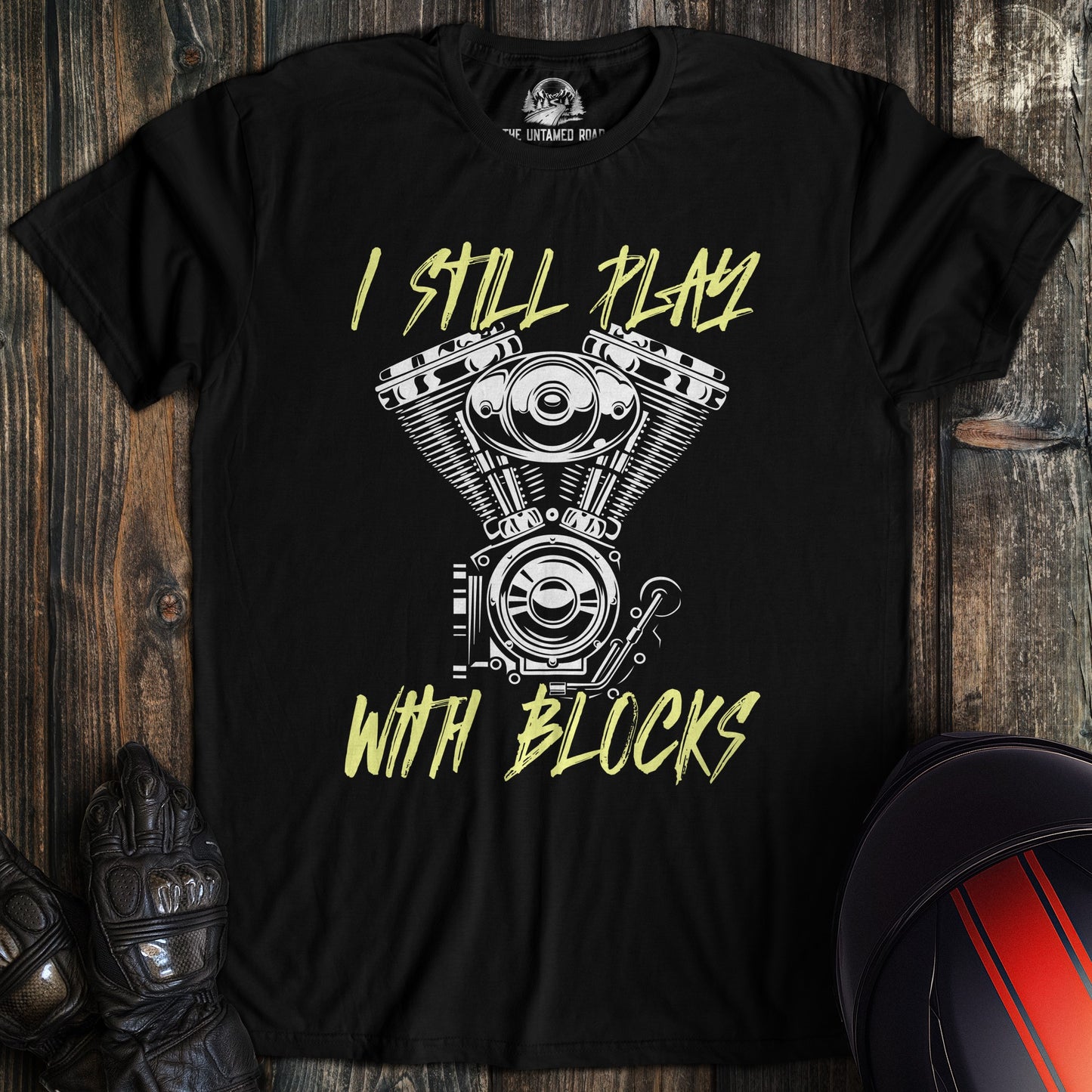 A black colored t-shirt with the words "still play with blocks" printed on the front.