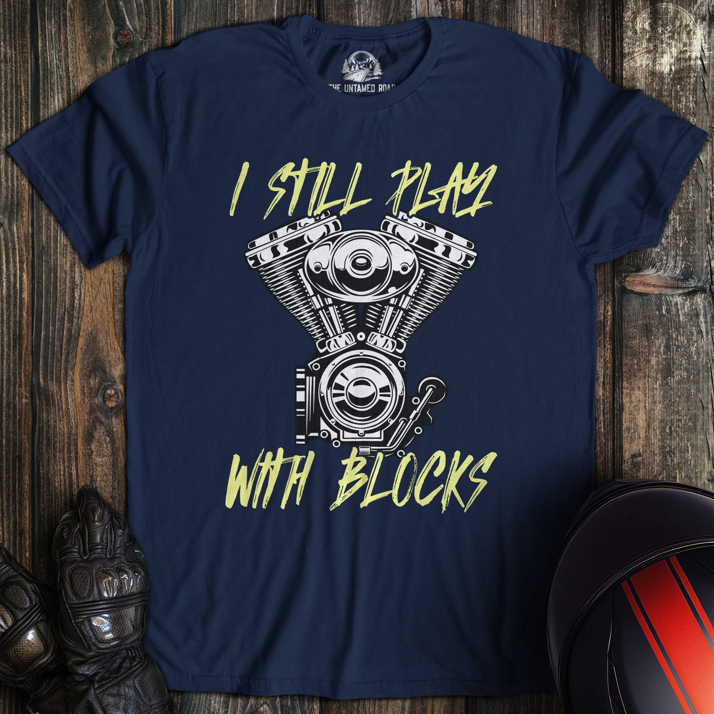 A navy colored t-shirt with the words "still play with blocks" printed on the front.