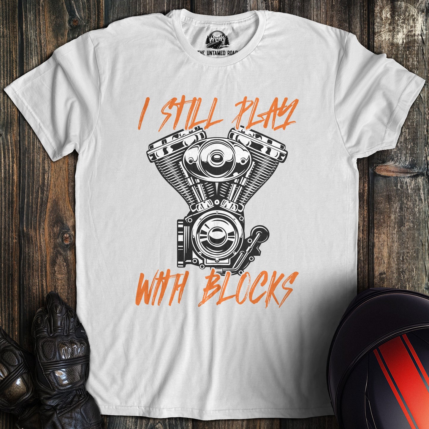 A white colored t-shirt with the words "still play with blocks" printed on the front.