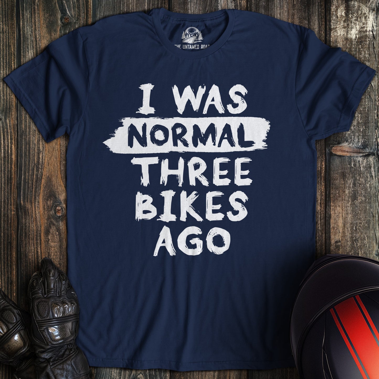 A navy colored t-shirt with the words "normal three bikes ago" printed on the front.