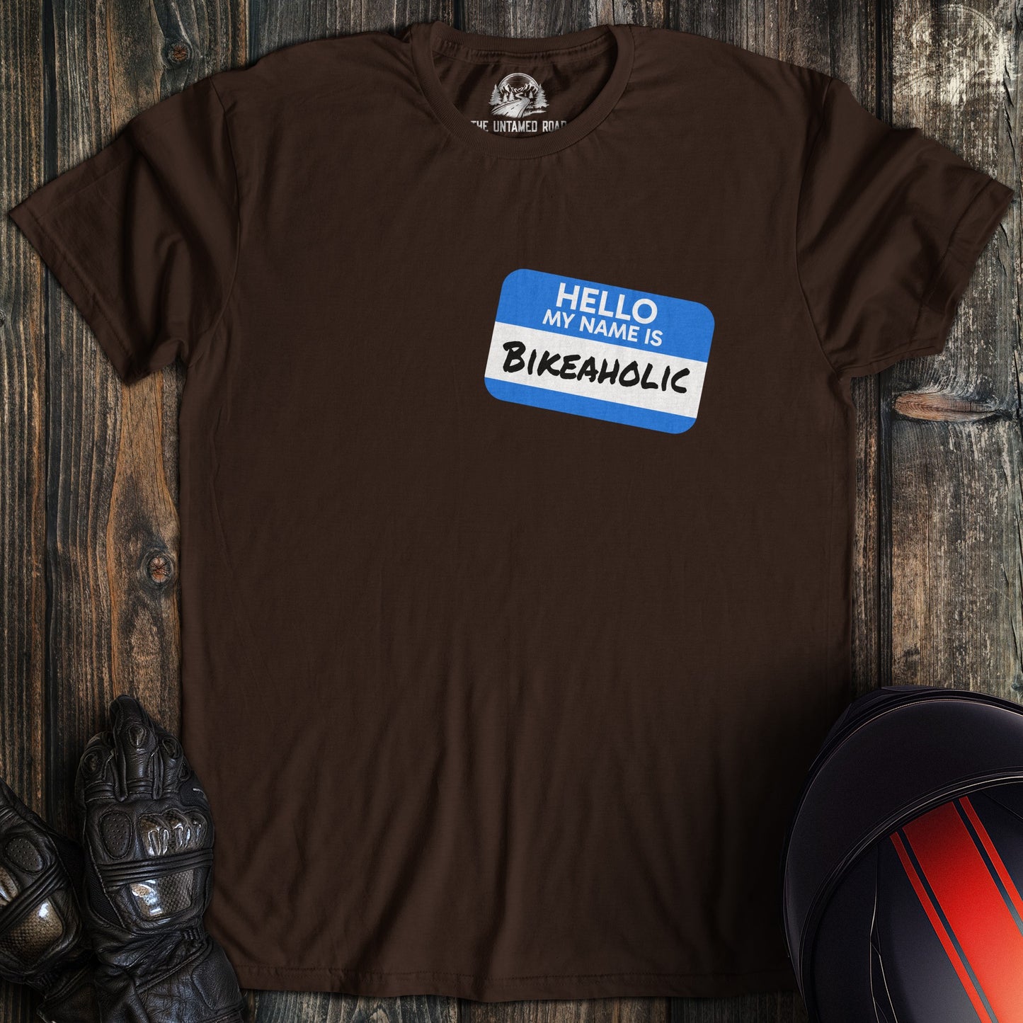A dark chocolate colored t-shirt with the words "bikeaholic nametag" printed on the front.