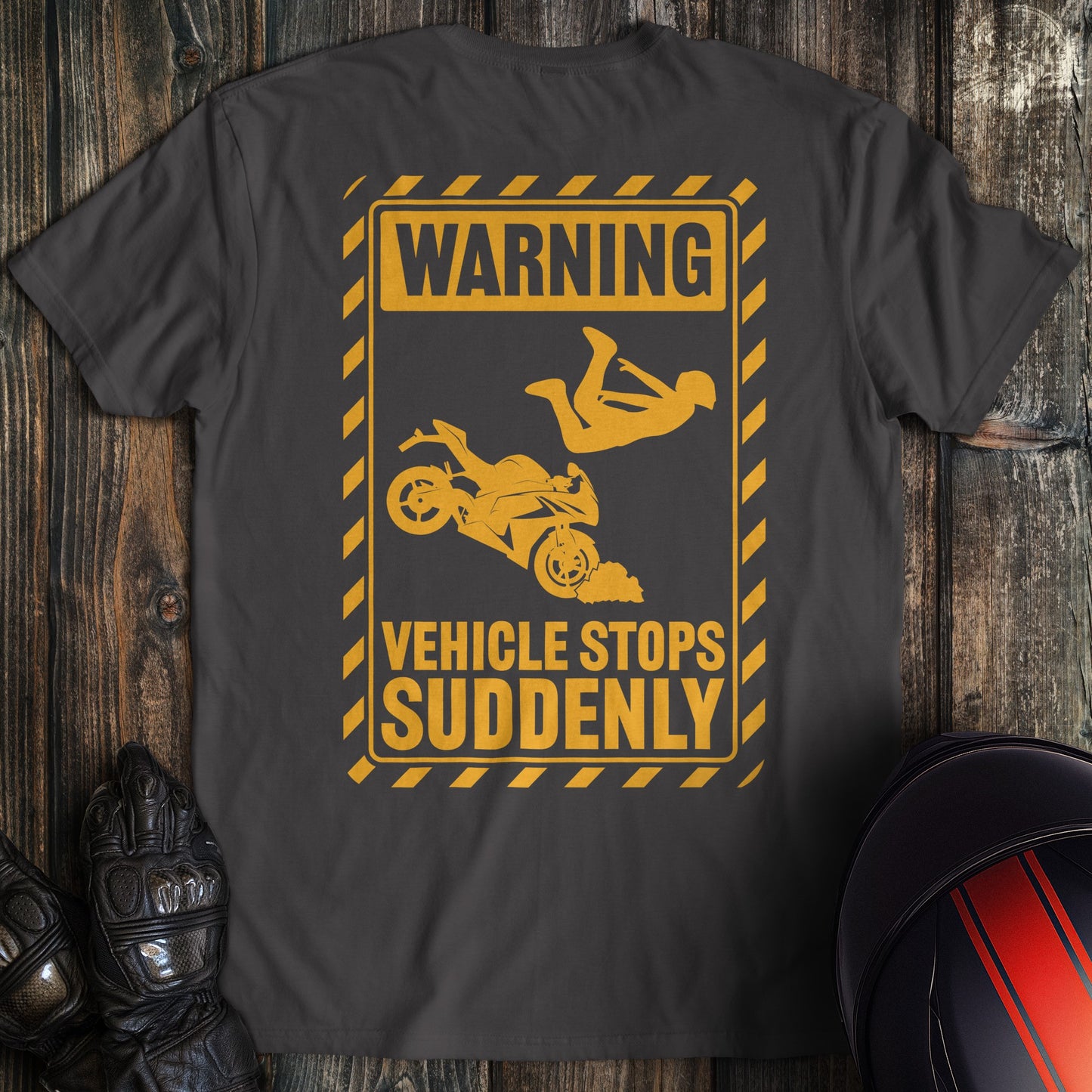 A charcoal colored t-shirt with the words "warning vehicle stops suddenly" printed on the back.
