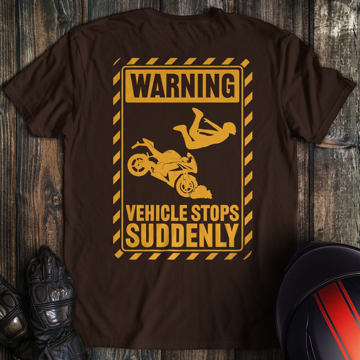 A dark chocolate colored t-shirt with the words "warning vehicle stops suddenly" printed on the back.