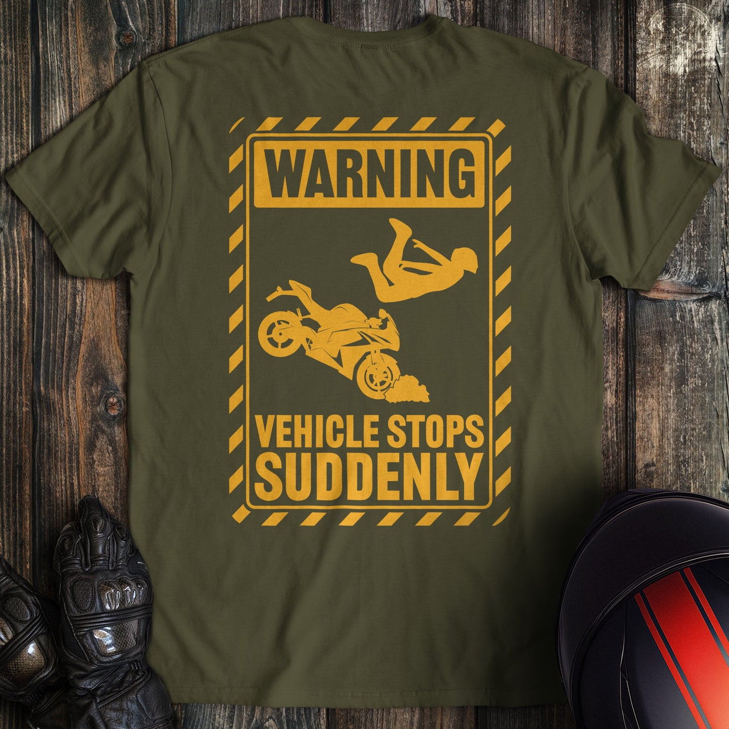 A military green colored t-shirt with the words "warning vehicle stops suddenly" printed on the back.