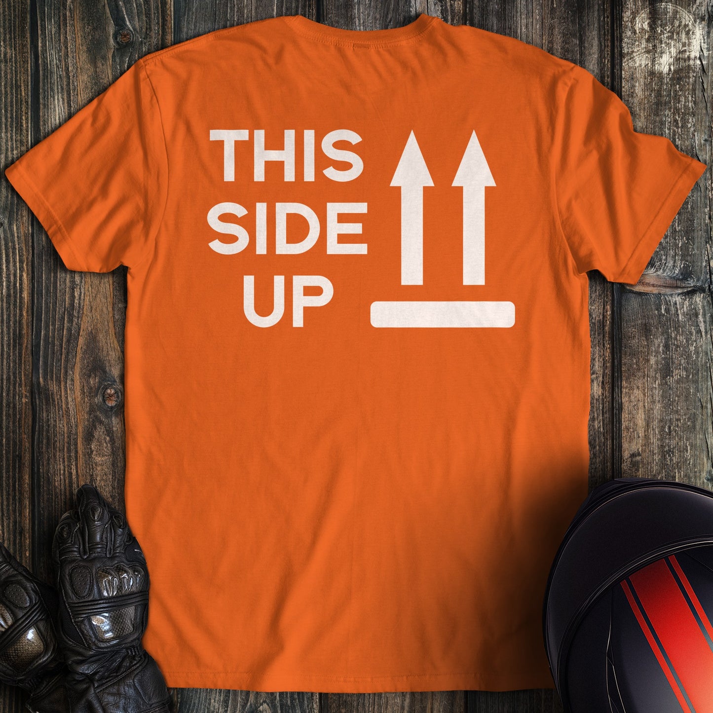 A orange colored t-shirt with the words "this side up" printed on the back.