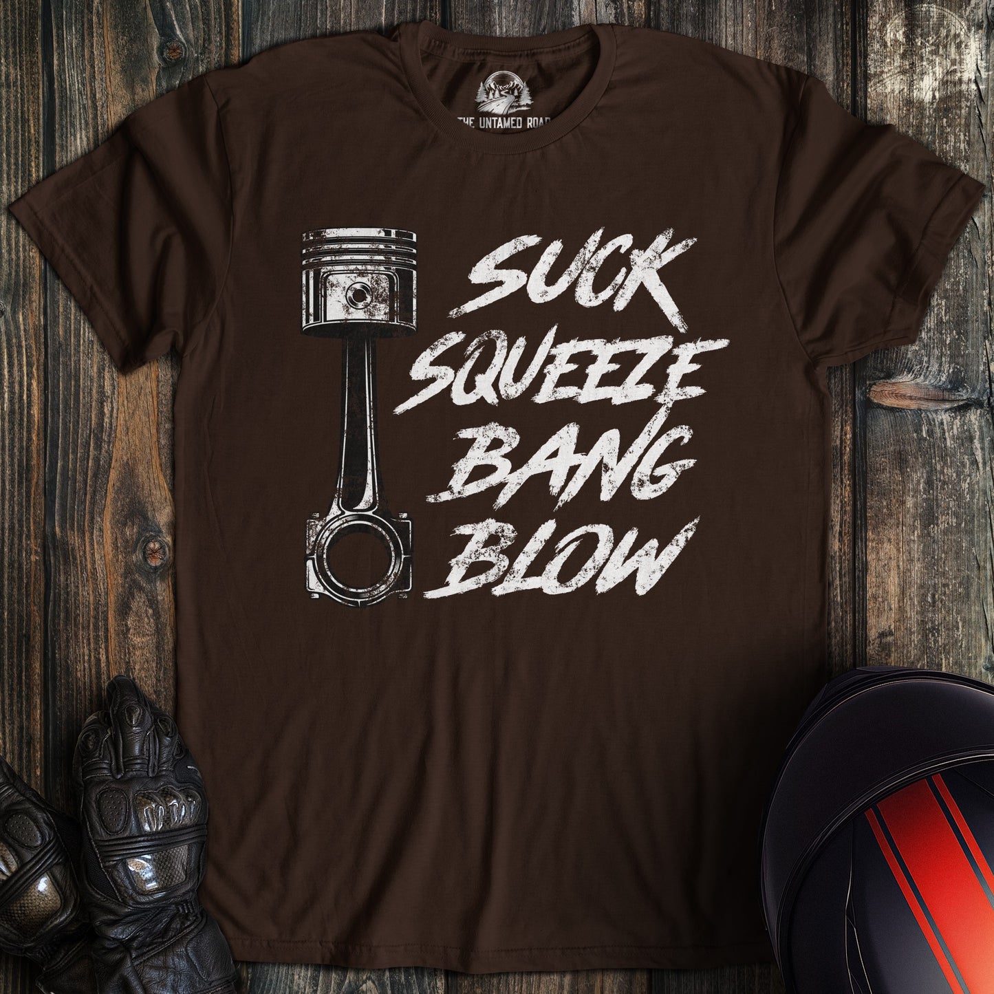A dark chocolate colored t-shirt with the words "suck squeeze bang blow" printed on the front.