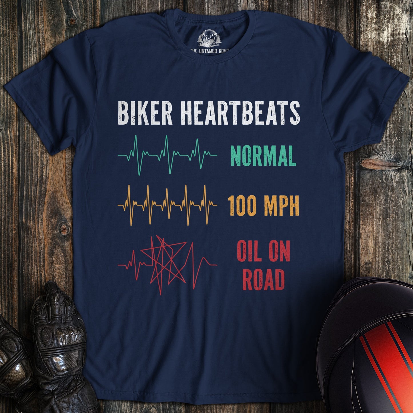 A navy blue biker t-shirt showing heartbeat lines for normal, 100 mph, and a chaotic red line for oil on road.