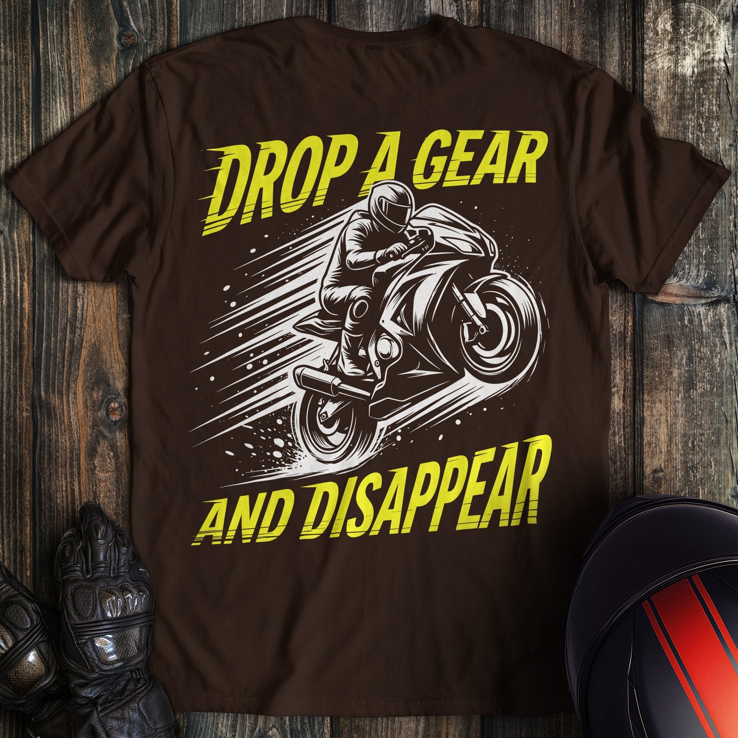 A dark brown t-shirt featuring a motorcycle graphic and the text Drop A Gear and Disappear in yellow.