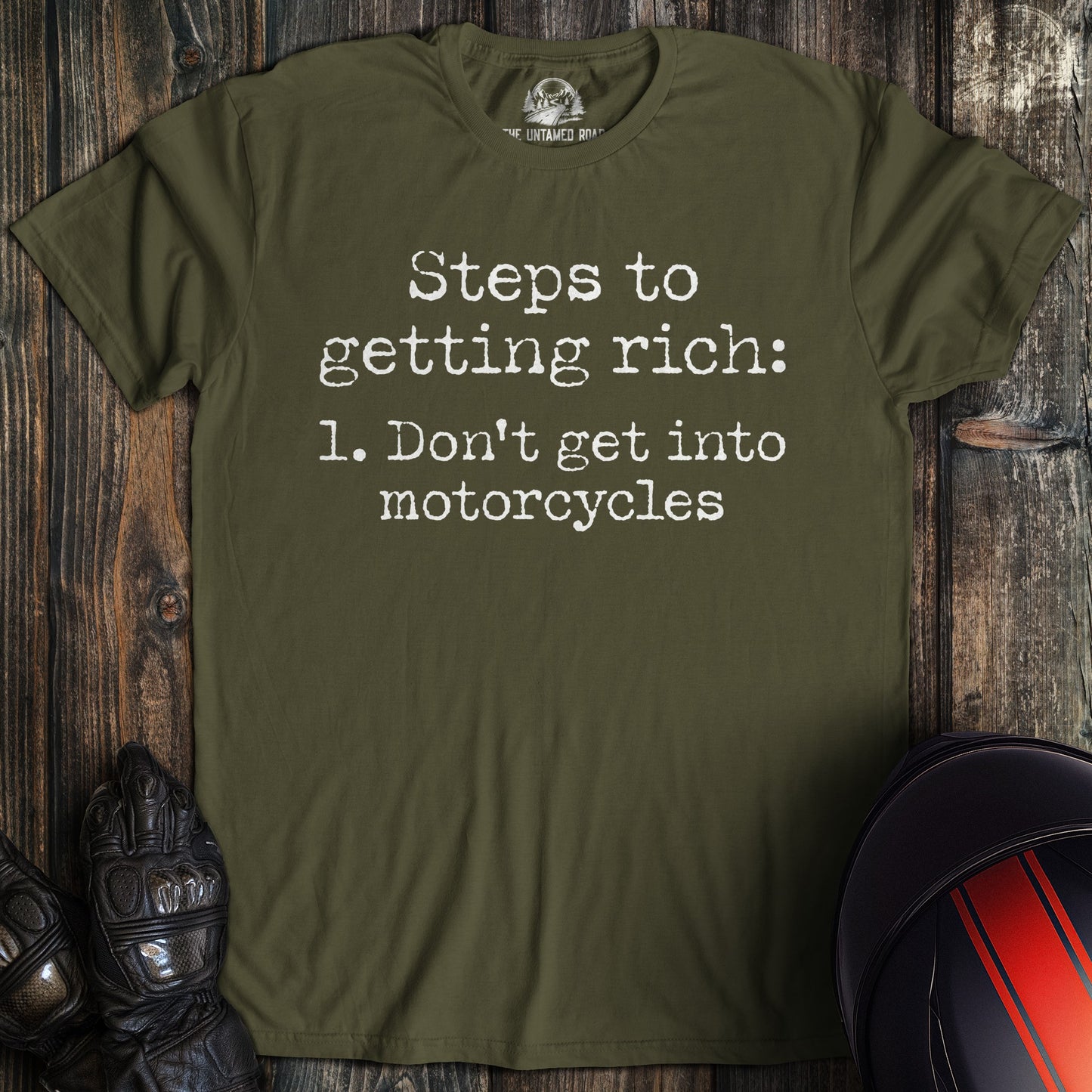 A military green t-shirt with white text that reads, Steps to getting rich: 1. Don't get into motorcycles.