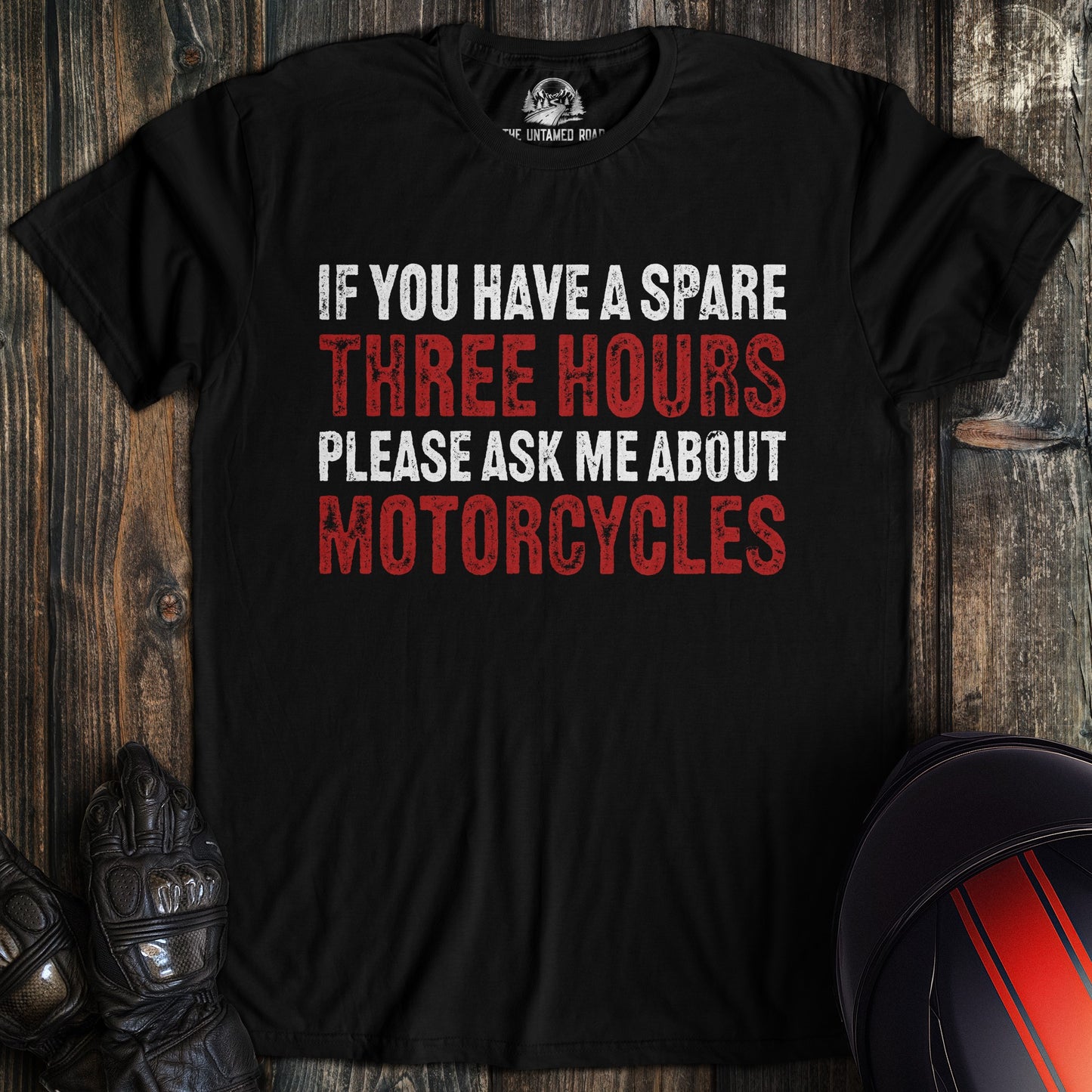 A black t-shirt with the text 'IF YOU HAVE A SPARE THREE HOURS PLEASE ASK ME ABOUT MOTORCYCLES' in white and red.