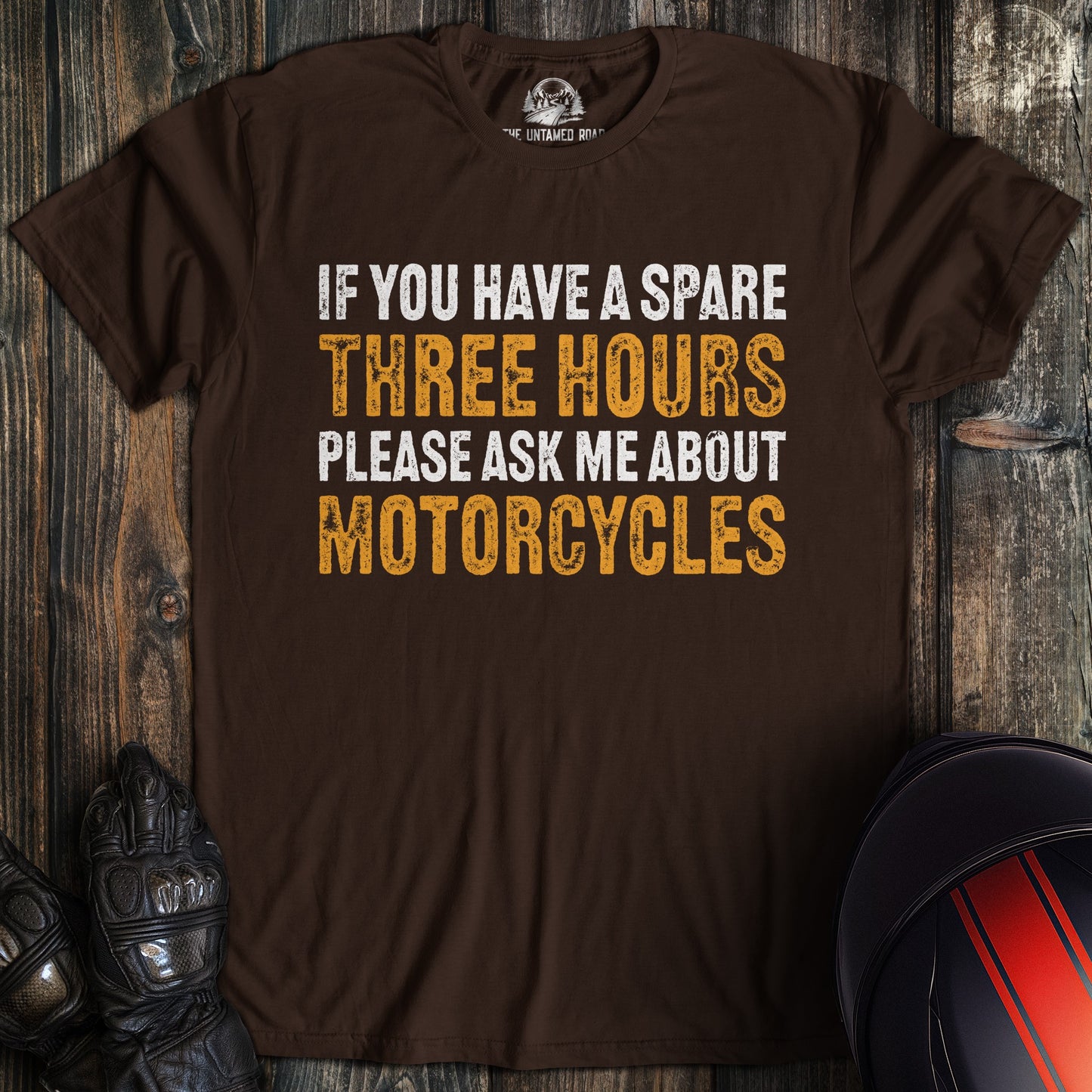 A dark brown t-shirt with the text 'If you have a spare three hours please ask me about motorcycles' in white and orange.