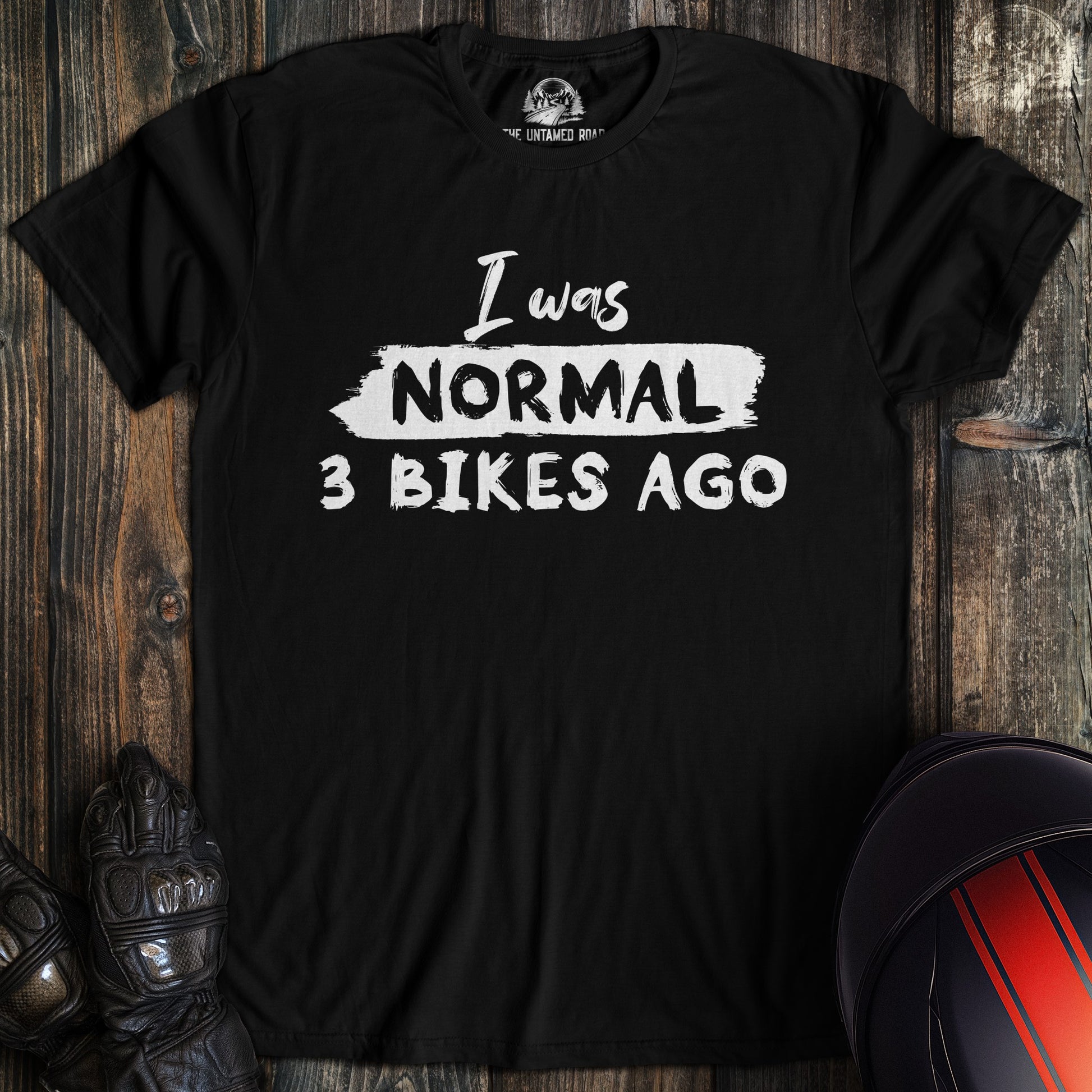A black colored t-shirt with the words "normal three bikes ago" printed on the front.