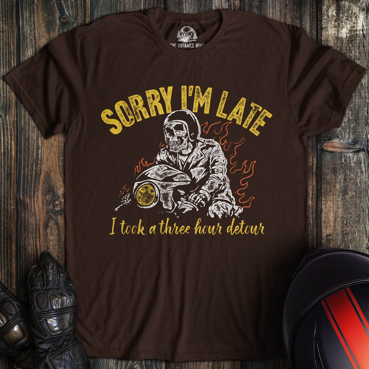 A dark brown t-shirt featuring a skeleton biker on a motorcycle with the text Sorry I'm Late I took a three hour detour.