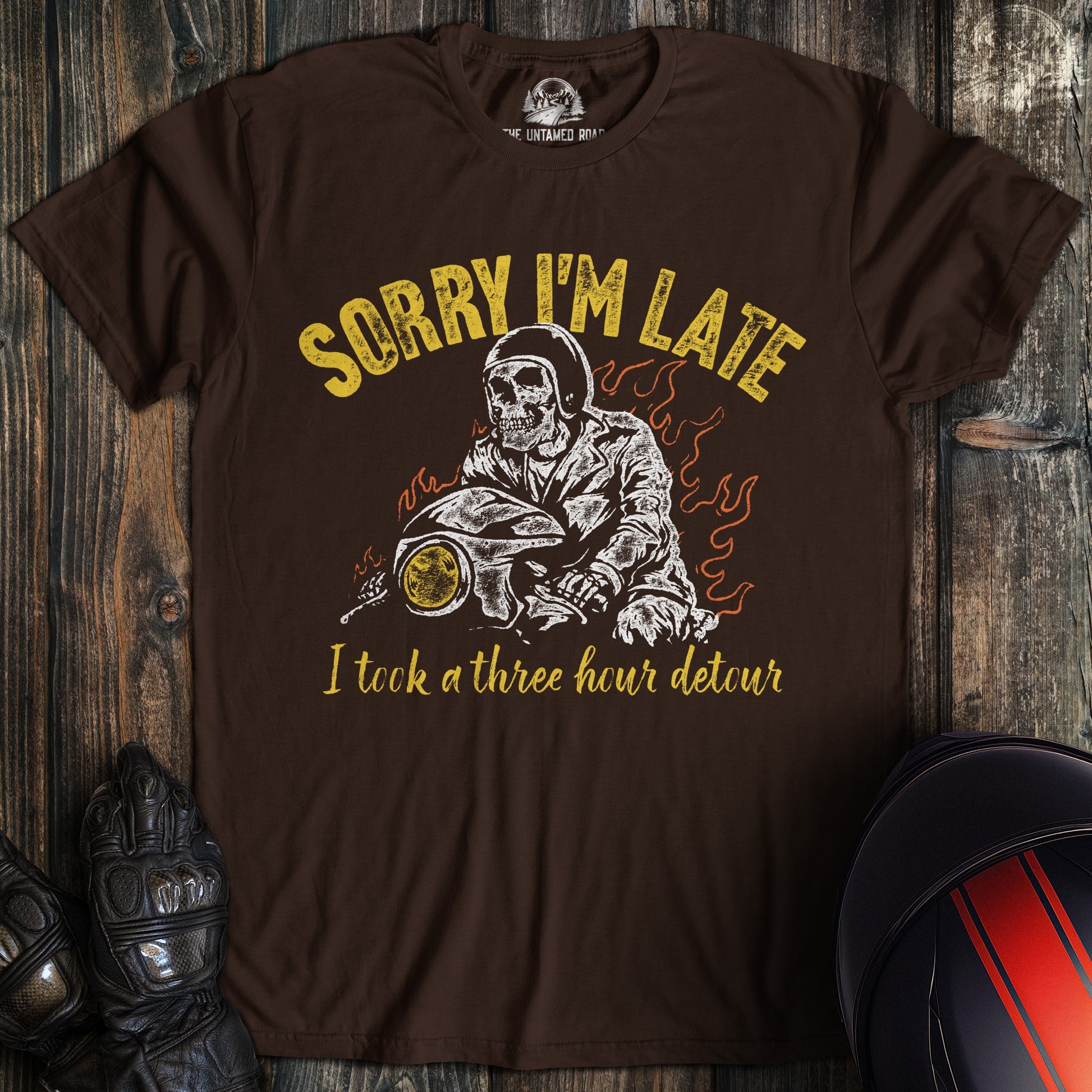 A dark brown t-shirt featuring a skeleton biker on a motorcycle with the text Sorry I'm Late I took a three hour detour.