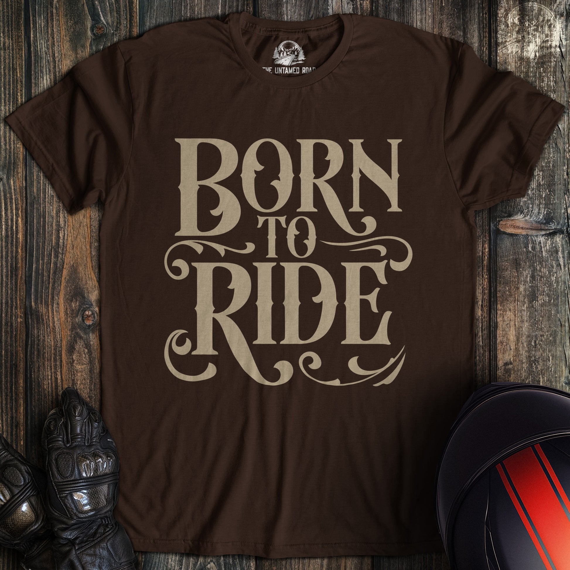 A dark chocolate colored t-shirt with the words "born to ride gothic" printed on the front.