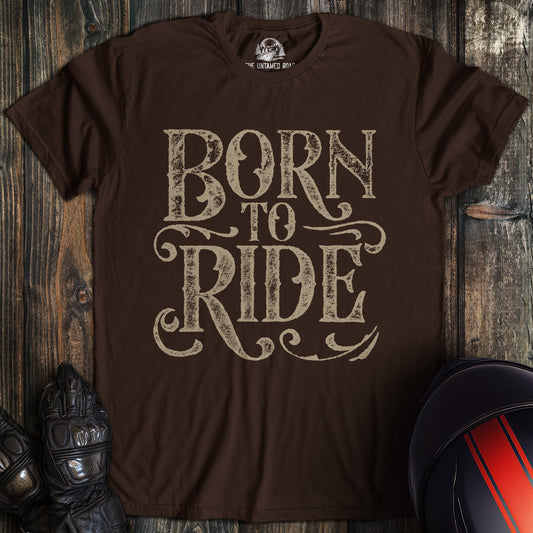 A dark chocolate colored t-shirt with the words "born to ride gothic grunge" printed on the front.