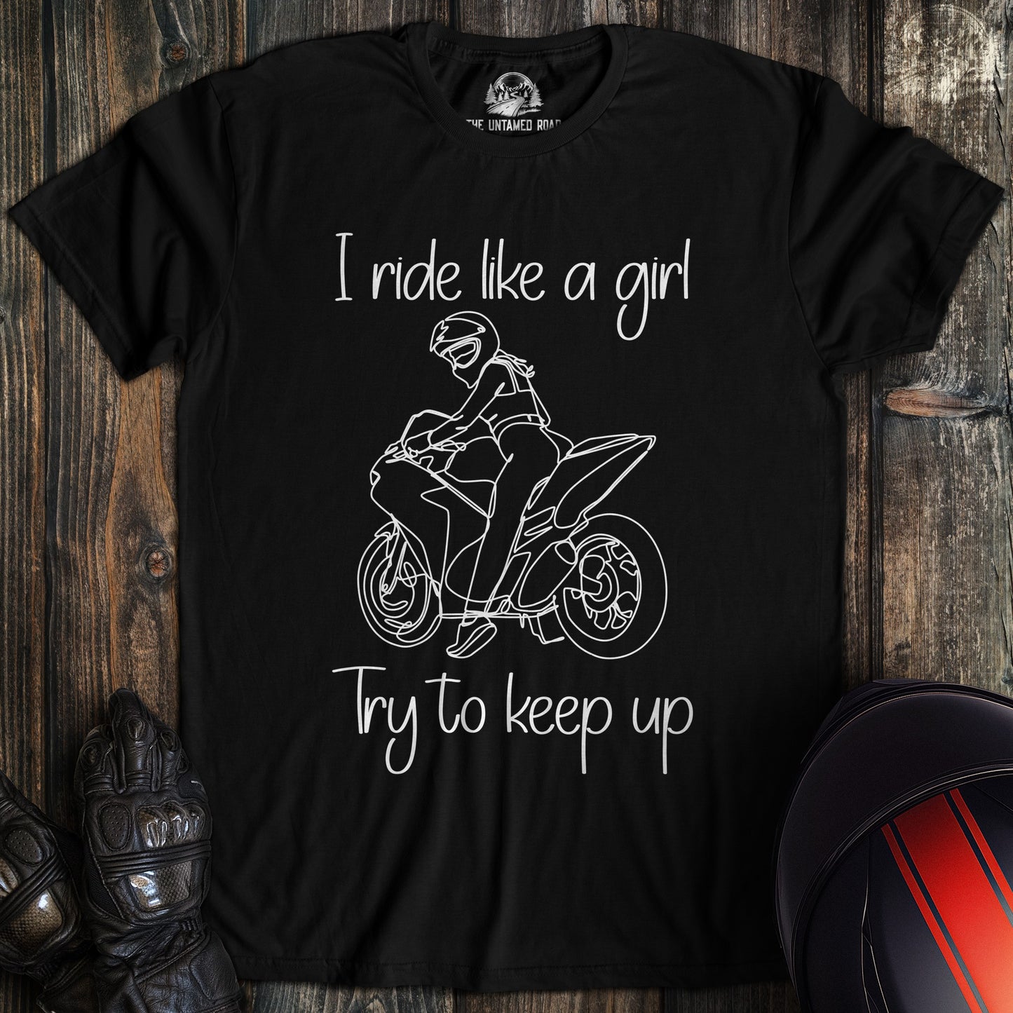 A black t-shirt featuring a white line drawing of a woman on a motorcycle with the text, I ride like a girl try to keep up.