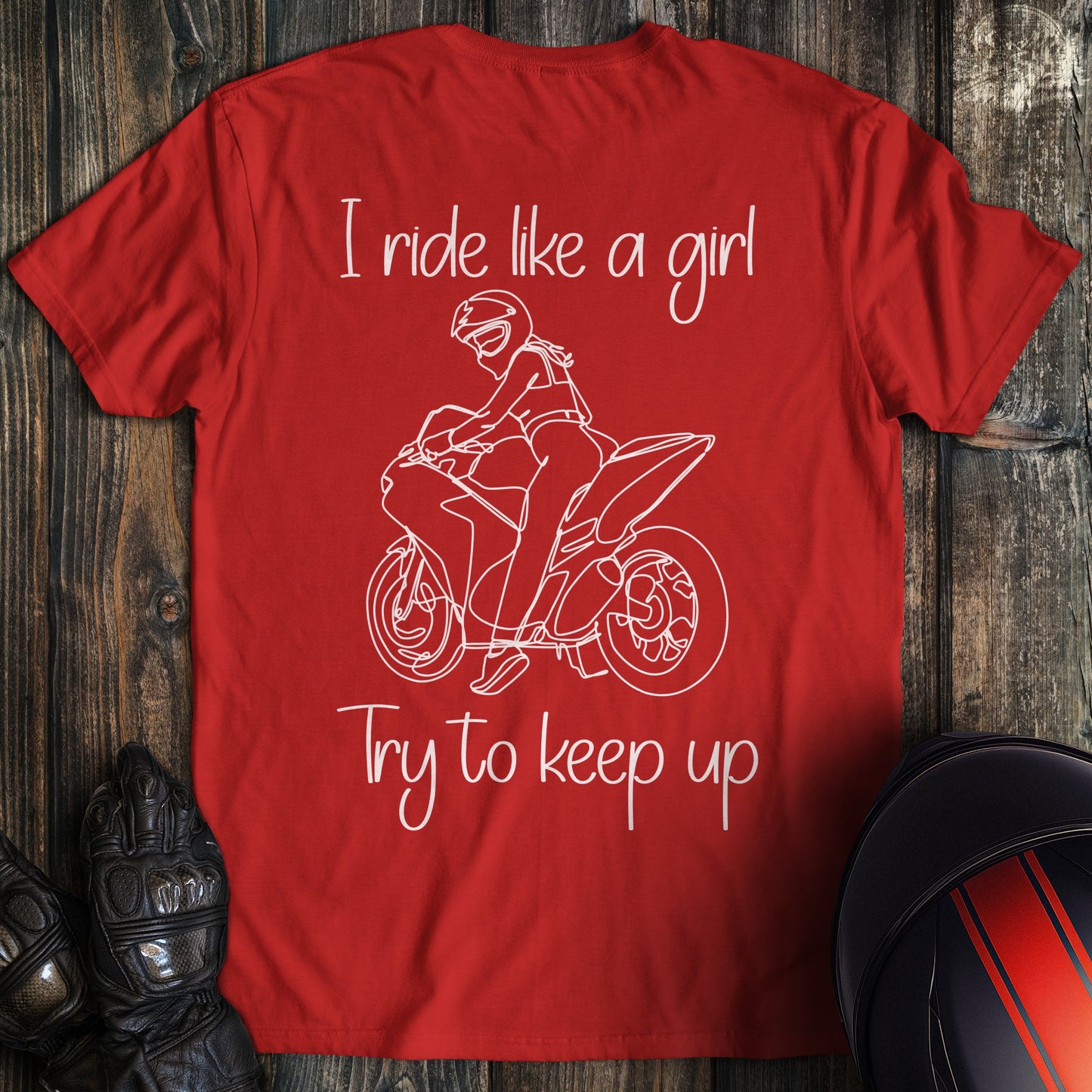 A red t-shirt featuring a white line drawing of a woman on a motorcycle with the text I ride like a girl Try to keep up.