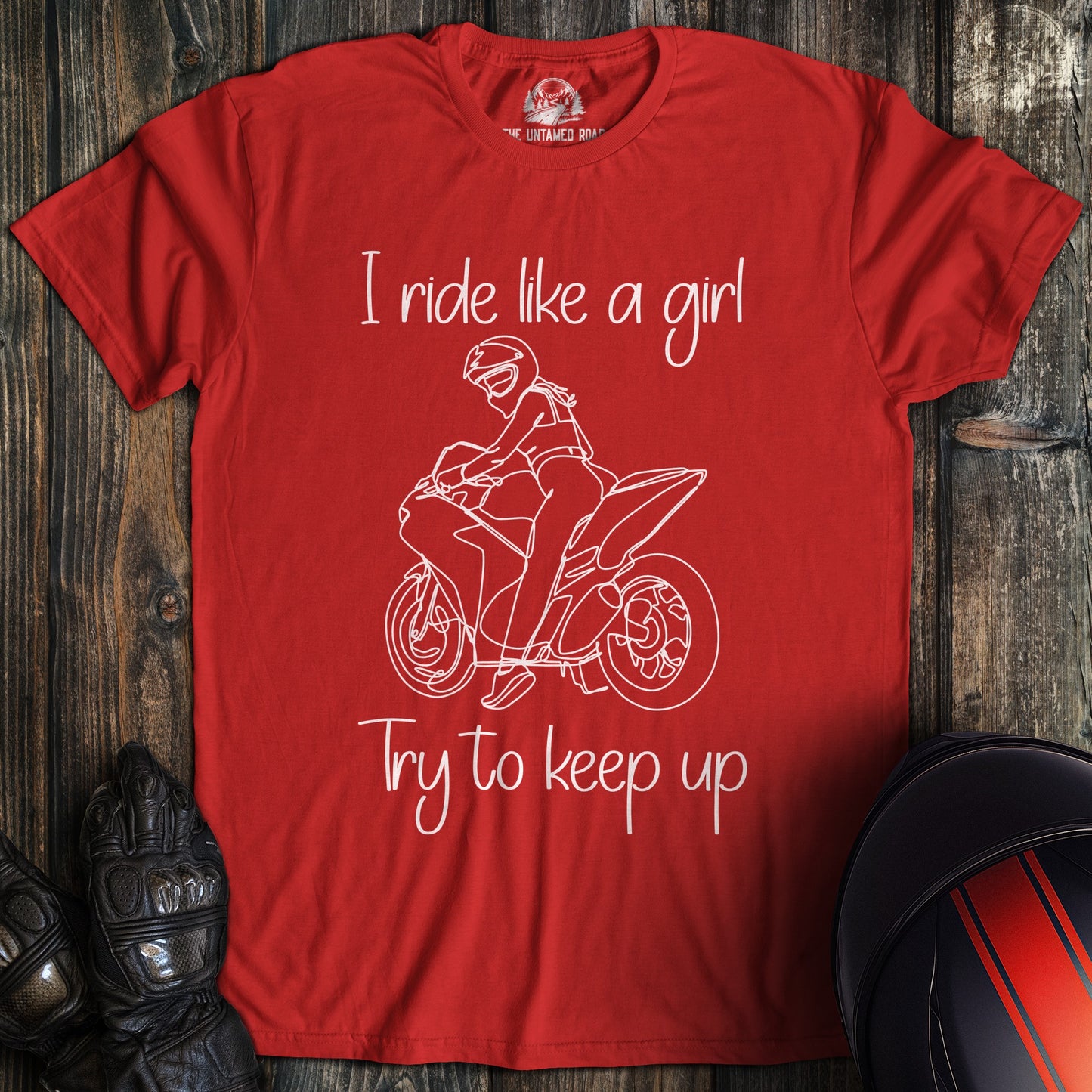A red t-shirt with a white line drawing of a biker on a motorcycle and the text, I ride like a girl Try to keep up.