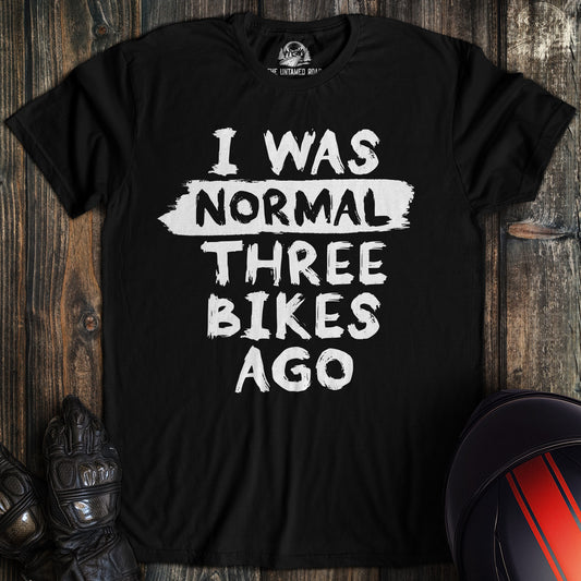 A black colored t-shirt with the words "normal three bikes ago" printed on the front.