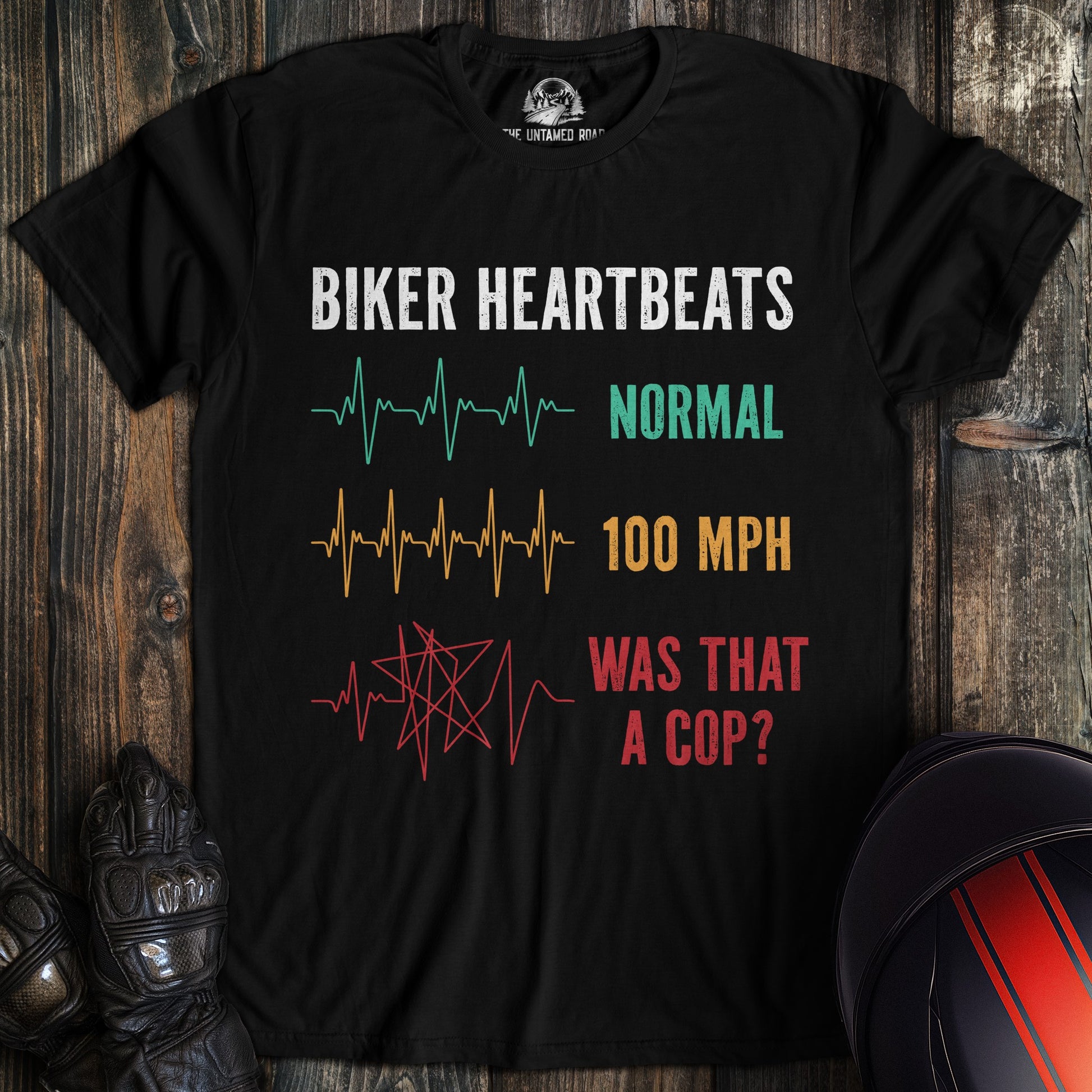 A black t-shirt featuring a funny biker heartbeats graphic with EKG lines for normal, 100 mph, and was that a cop.