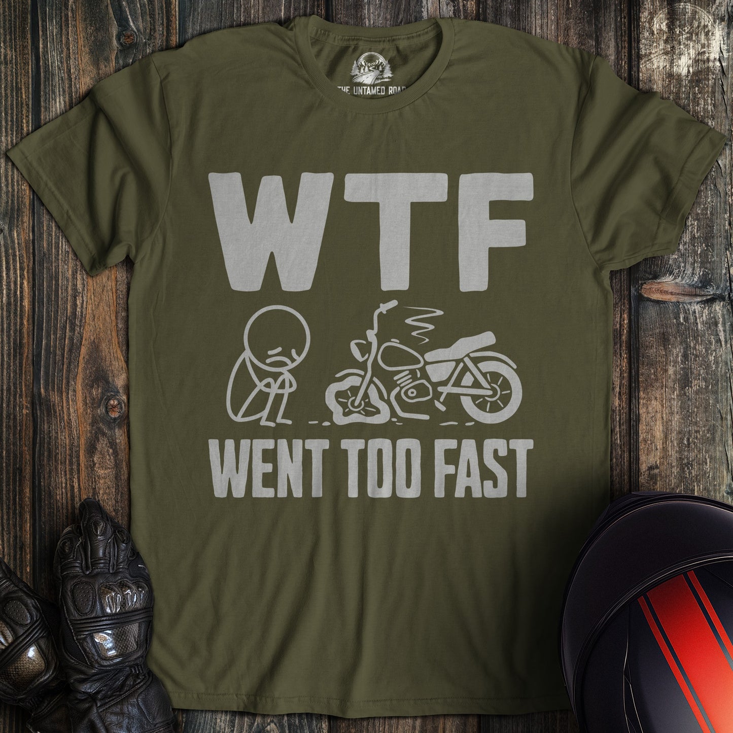 A military green t-shirt with a funny graphic of a sad biker next to a crashed motorcycle and the text WTF Went Too Fast.