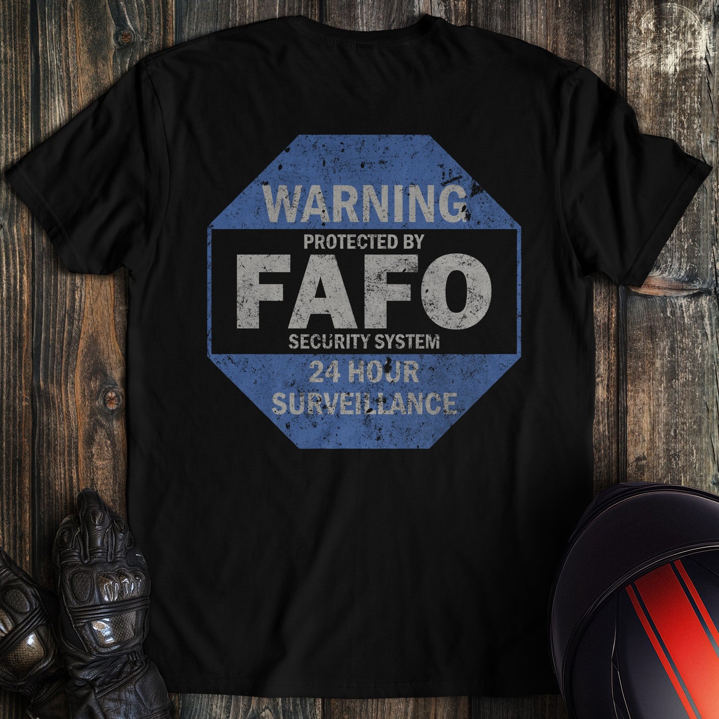 Back of a black t-shirt with a blue octagonal sign reading Warning Protected by FAFO Security System 24 Hour Surveillance.