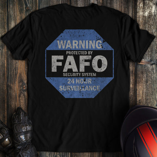Back of a black t-shirt with a blue octagonal sign reading Warning Protected by FAFO Security System 24 Hour Surveillance.