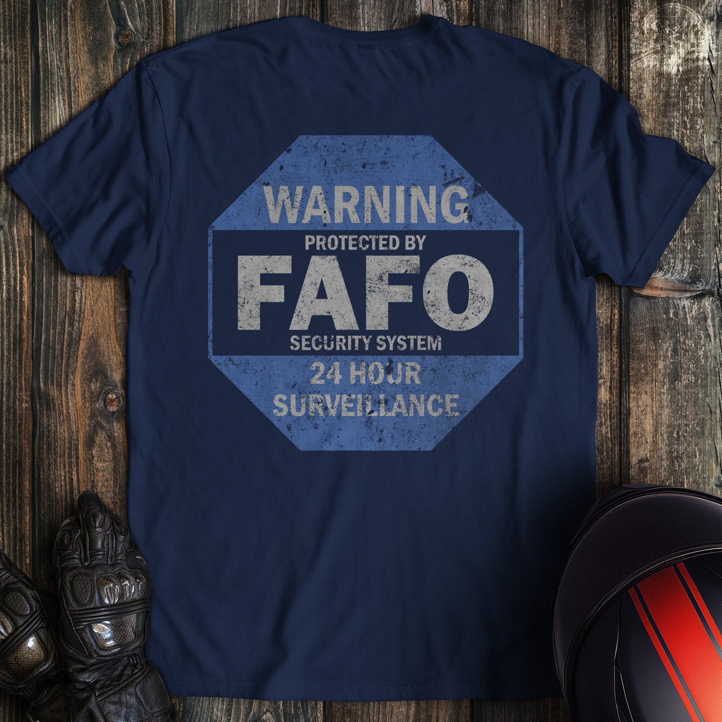 Back of a navy blue t-shirt with a distressed octagonal graphic reading Warning Protected by FAFO Security System.