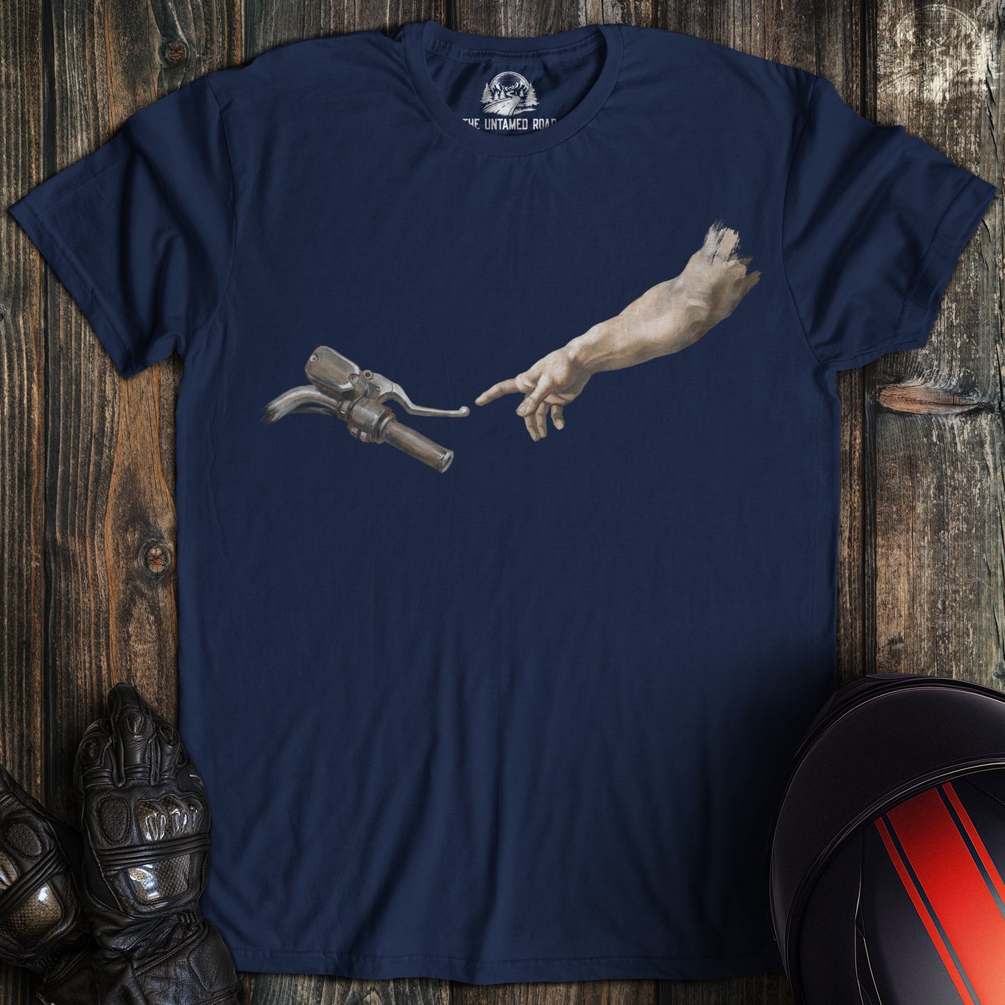 A navy blue t-shirt featuring a graphic of a hand reaching toward a motorcycle handlebar in a parody of The Creation of Adam.