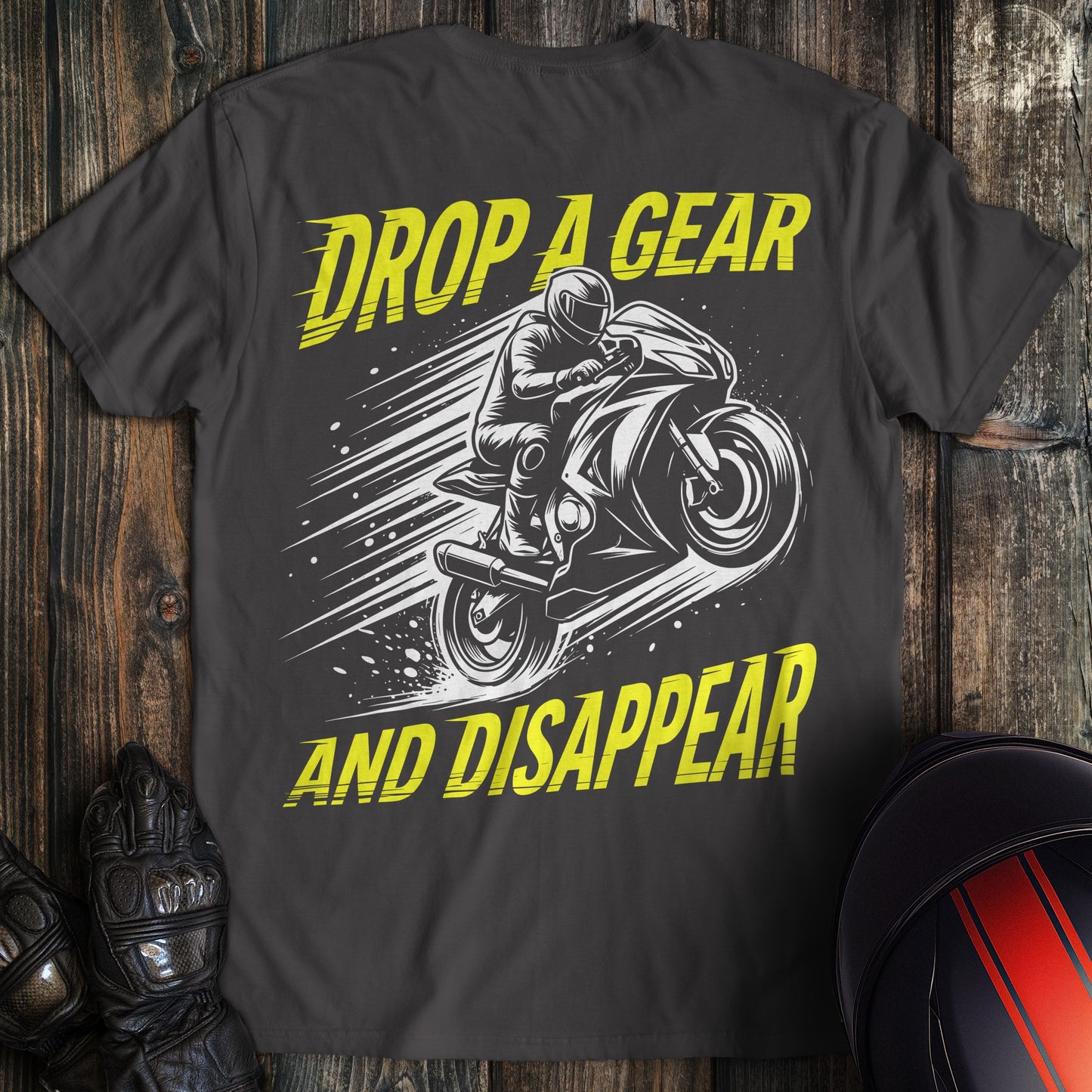 Charcoal gray t-shirt with a yellow and white graphic of a motorcycle rider and the text Drop A Gear And Disappear.