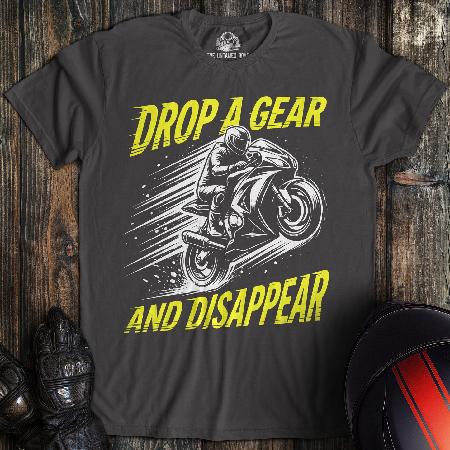 A charcoal gray t-shirt featuring a biker on a motorcycle with the text Drop A Gear And Disappear in yellow.