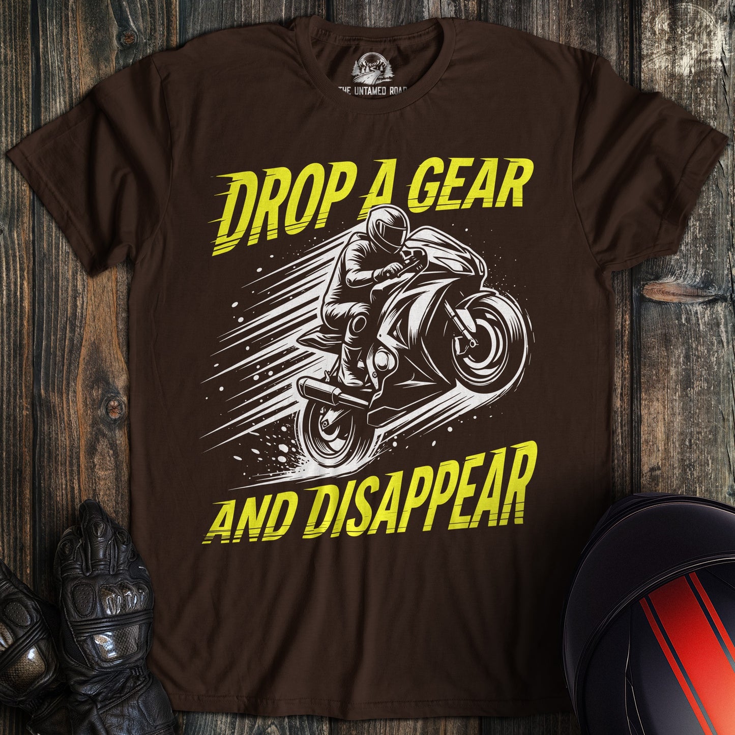 A dark brown t-shirt featuring a motorcycle graphic and the text Drop A Gear And Disappear in yellow.
